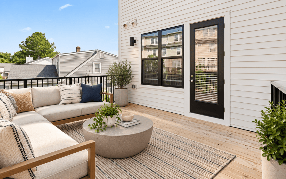 Staged private outdoor deck at Alta NOVA's C4 floor plan featuring comfortable lounge seating, a contemporary coffee table, wood decking, and black metal railings.