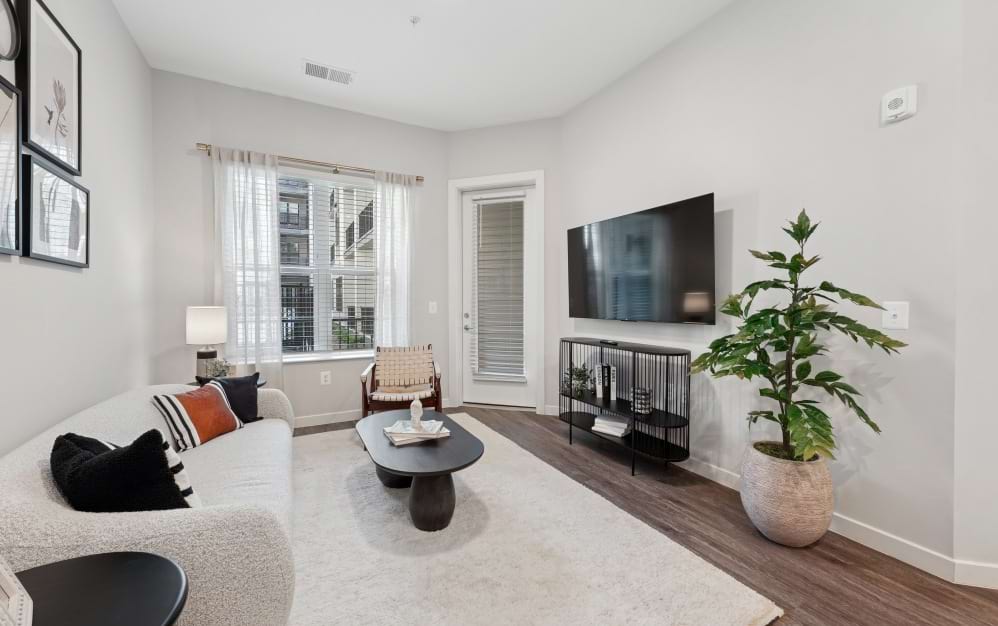 Bright living room in the A8 one-bedroom apartment at Alta NOVA with wood-style flooring and access to a private balcony.