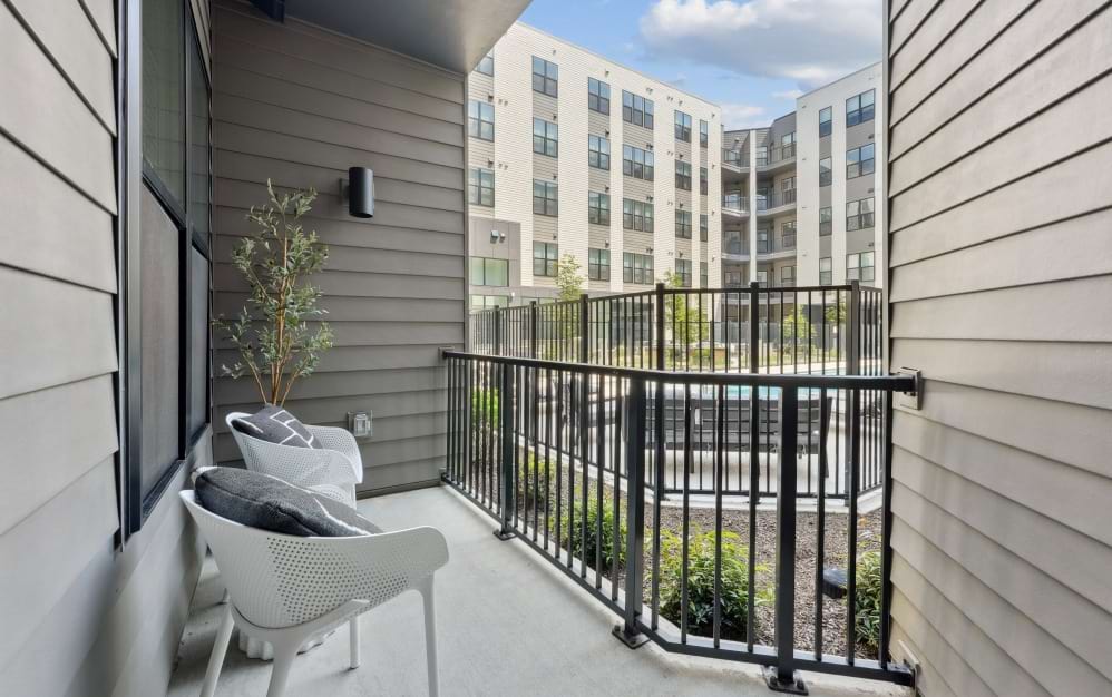 Private balcony in the A8 one-bedroom apartment at Alta NOVA with outdoor seating and views of the community courtyard.