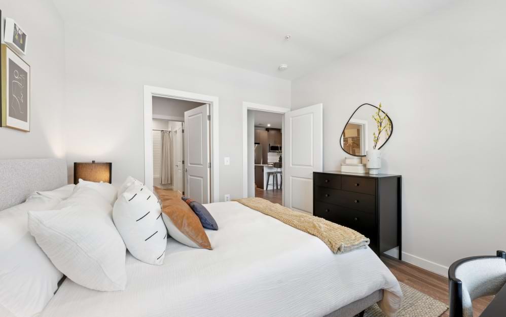 Spacious bedroom in the A8 one-bedroom apartment at Alta NOVA with wood-style flooring and convenient access to the bathroom and closet.
