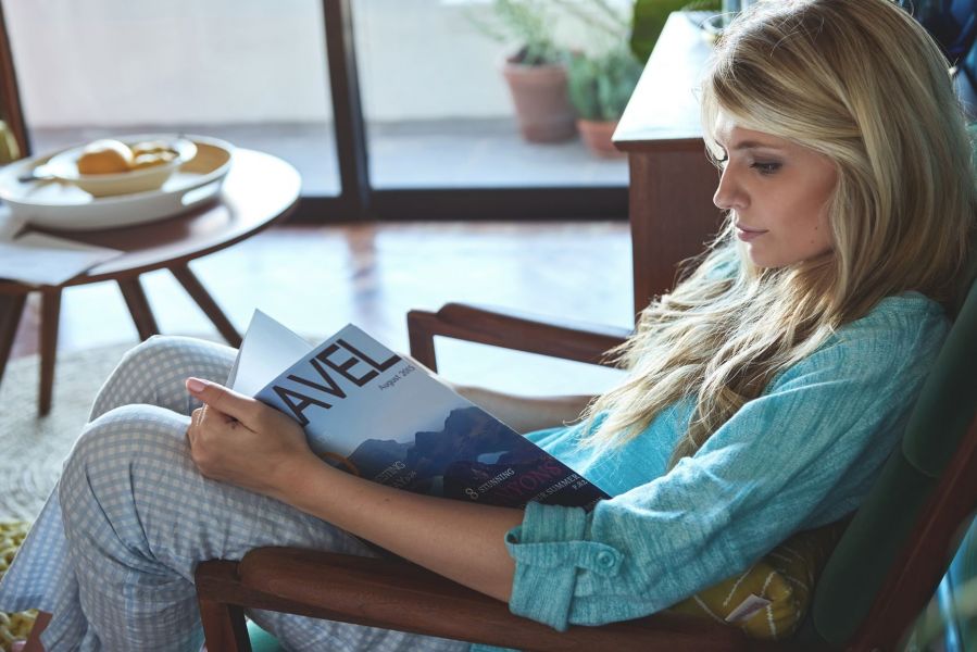 Woman living alone, reading in the cosy comfortable retro mid century styled apartment