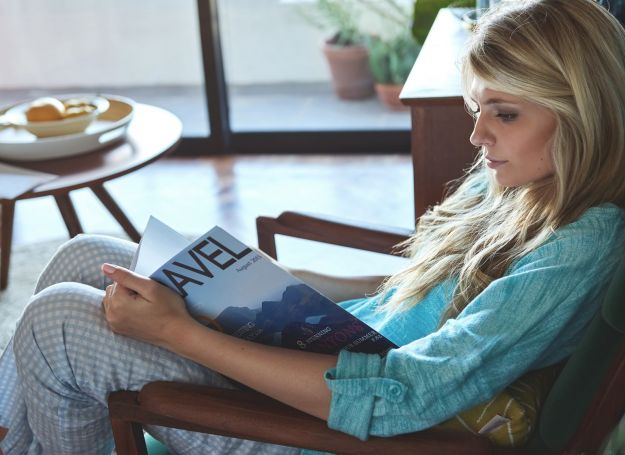 Woman living alone, reading in the cosy comfortable retro mid century styled apartment