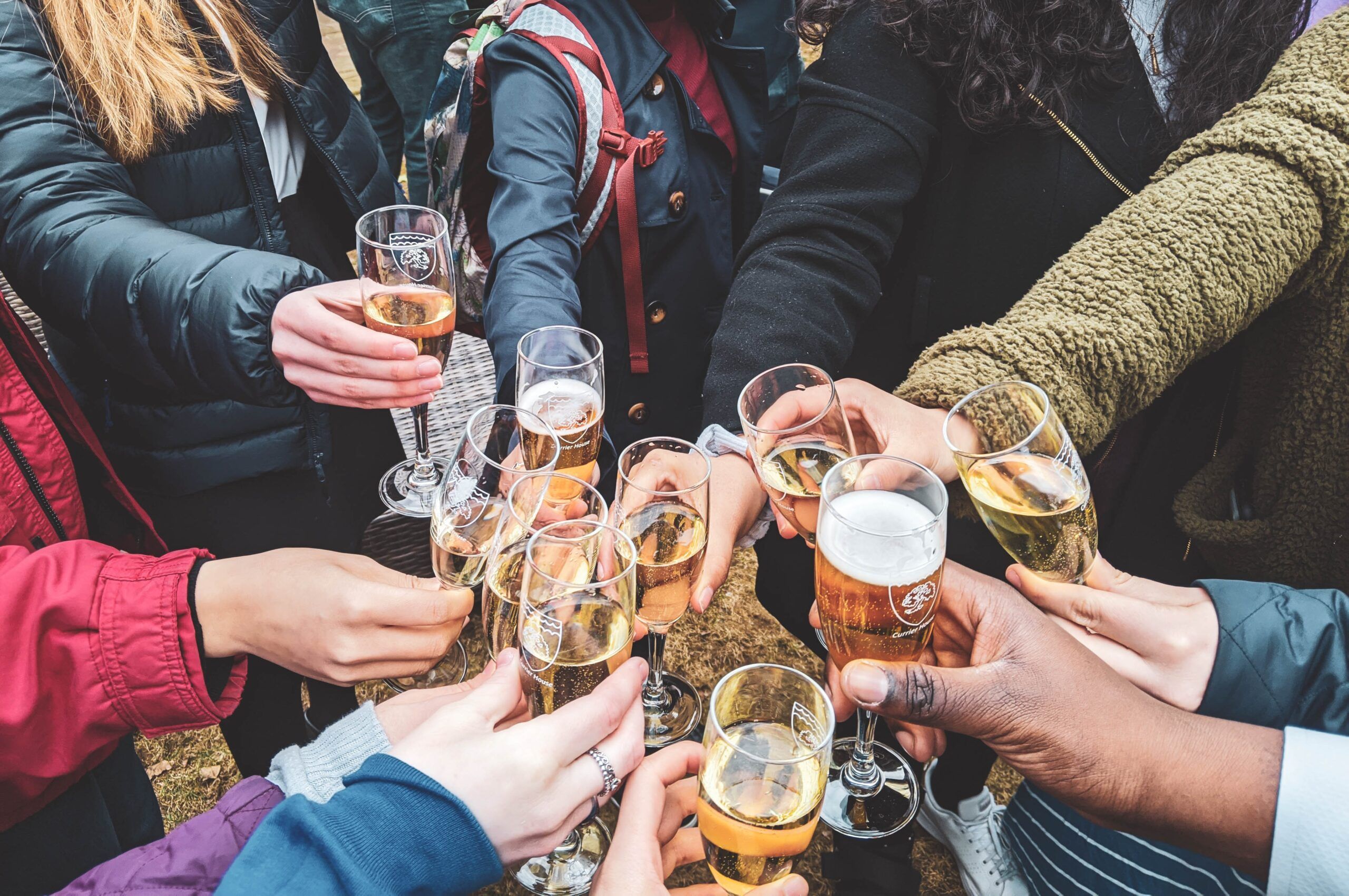 A group of people at Alta Nova apartments clinking glasses of champagne together in a celebratory toast outdoors.