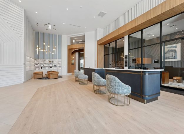 Alta Nova apartments Modern office lobby with sleek counters, stylish chairs, lounge seating, and floor-to-ceiling windows.
