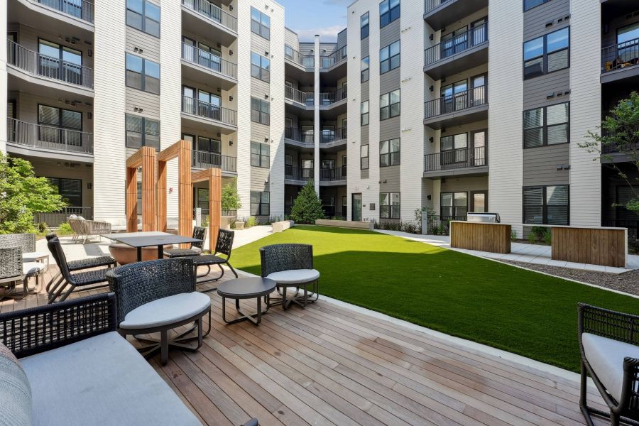 Alta Nova apartments  Modern apartment courtyard with seating, green lawn, and dining area surrounded by multi-story buildings.